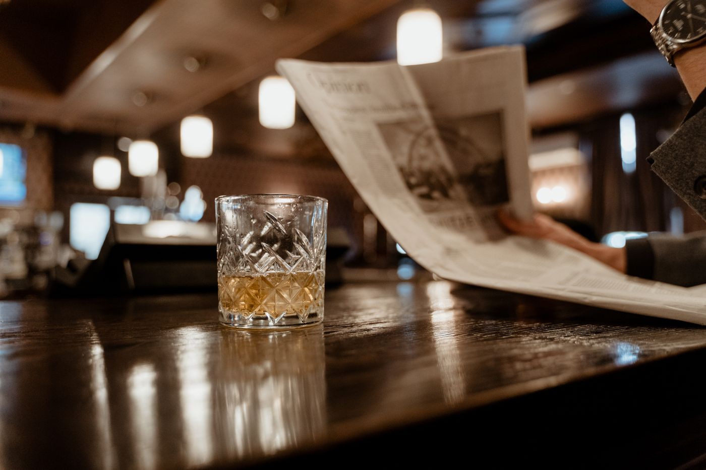 Crystal whiskey glass on a warm-lit bar counter
