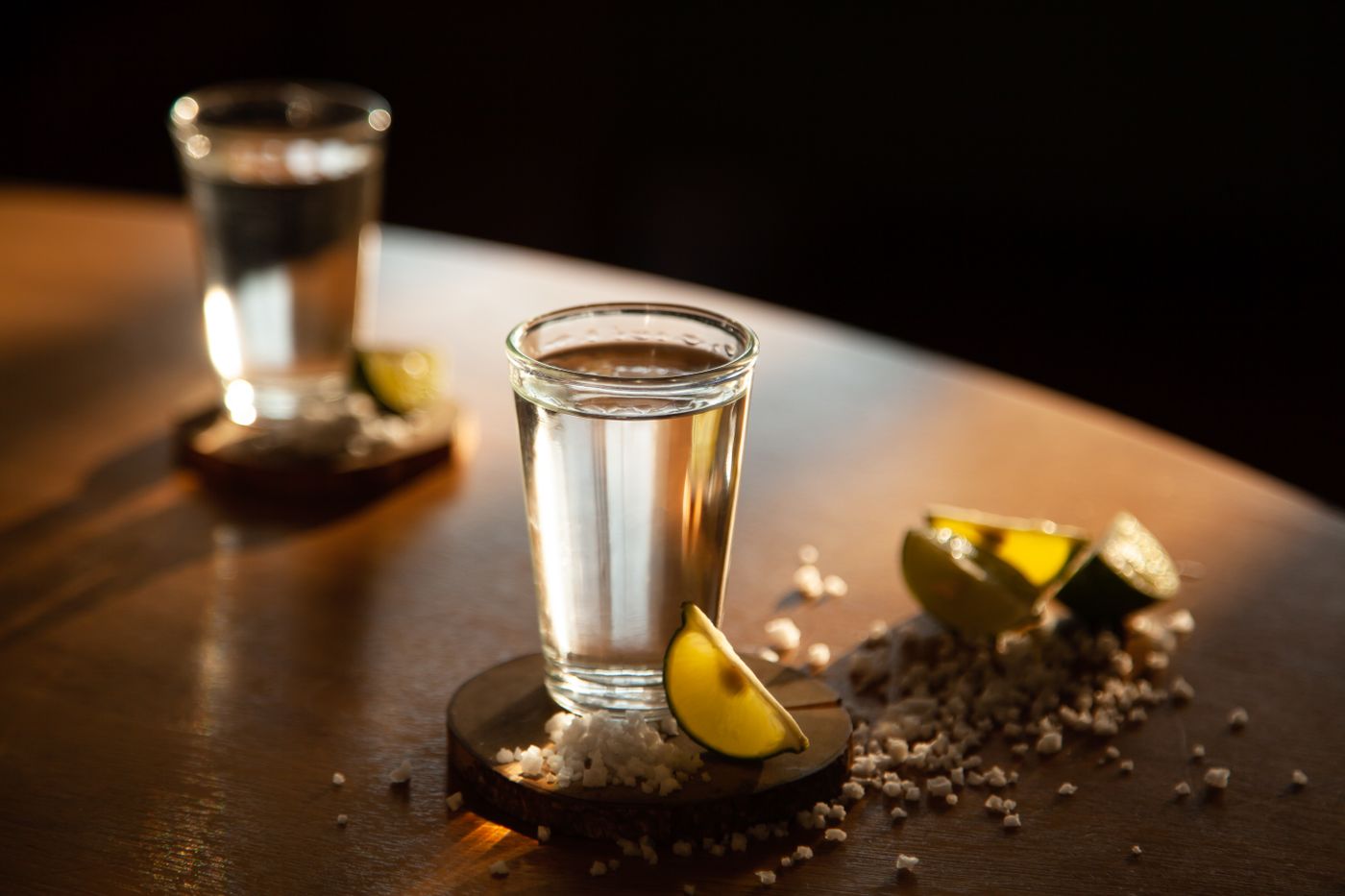 Tequila shot with salt and lime in warm candlelight